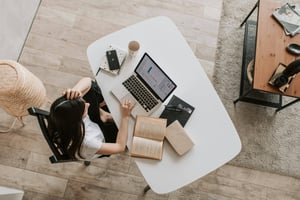 Female preparing online event on a notebook at home. table top view. 